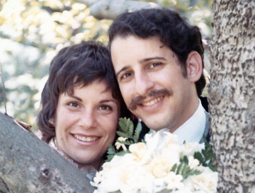 Margie and Larry posing behind a tree