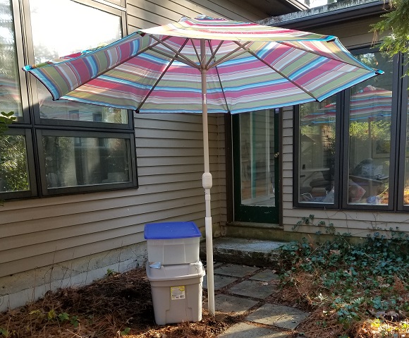 A beach umbrella outside the sunroom door, over an improvised table